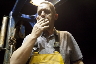 Jim Wood, the skipper, smokes a cigarette at the stern of the Launch Out in the evening in October 2011 after hauling the net.