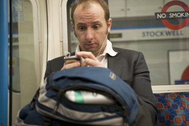 Commuter listening to his ipod on the London underground while the train stops at Stockwell station in February 2010, England.